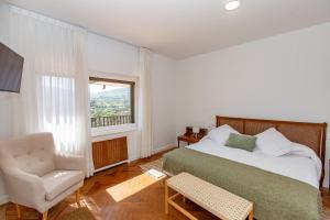 a bedroom with a bed and a chair and a window at Finca Tolombreo Casa Gabriel in Cudillero