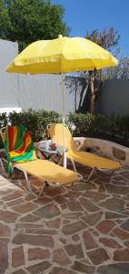two chairs and a table with a yellow umbrella at Jasmine Home, Aegina City in Egina
