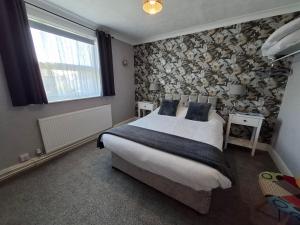 a bedroom with a large bed with a floral wallpaper at Westbrook Lodge Guest House in Margate