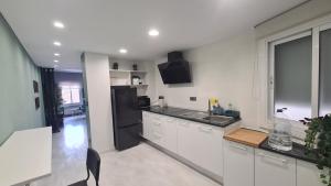 a kitchen with white cabinets and a black refrigerator at The Green House in Zaragoza