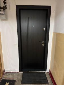 Una puerta negra con una alfombra negra delante. en Central Chic Apartment, en Galaţi 4 fotos más