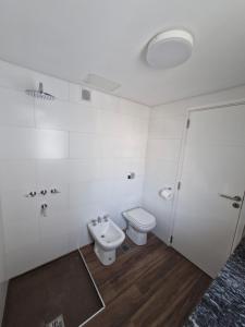 a white bathroom with a toilet and a sink at Agradable departamento in Cordoba
