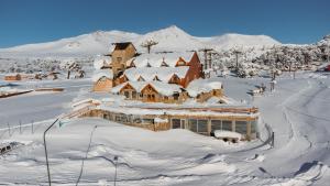 a house covered in snow with a mountain in the background at Hotel Spa Nieves Del Cerro in Caviahue