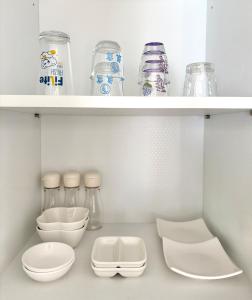 eine Küche mit weißen Regalen mit Gläsern und Schüsseln in der Unterkunft Yeondam Stay in Seoul