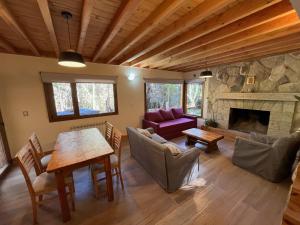 a living room with a table and a fireplace at LOS HUEMULES - casa nueva en medio del bosque y a pasos del centro de la ciudad- in San Carlos de Bariloche