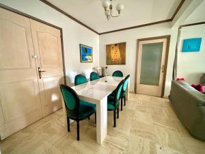 jadalnia z białym stołem i zielonymi krzesłami w obiekcie Évasion aux Portes de Cannes 100m2 Lumineux 2 Chambres Terrasse et Commerces w mieście Le Cannet
