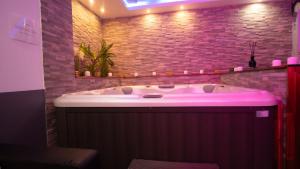 a bath tub in a bathroom with a brick wall at Suite avec Jacuzzi Privatif-Golden Jacuzzi in Léguevin