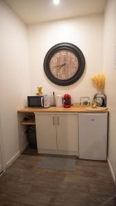a clock hanging on a wall above a counter with a kitchen at Suite avec Jacuzzi Privatif-Golden Jacuzzi in Léguevin +4 photos