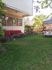 a house with a table and a bench in the yard at The Abode2 Entebbe in Entebbe