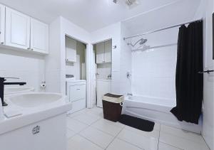 Un baño blanco con bañera y lavabo. en Élégant et cosy - 2 chambres bien équipé et parking gratuit, en Montreal