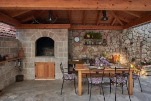 a dining room with a table and a stone wall at Cavtat Micika Apartment in Zvekovica