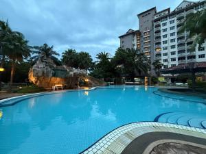 a large blue swimming pool with buildings in the background at ERICCA 3 Bedroom Seaview Suite, Glory Beach Resort, PD in Port Dickson