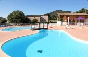 a large swimming pool with a house in the background at Maisonnette Sous les chênes GARD 30 in Sauve