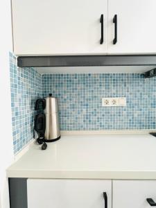 a kitchen with white cabinets and blue tiles at Alara loft in Antalya