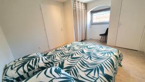a bedroom with a bed with a green and white blanket at Le Mûrier - clim, parking, accès direct voie verte in Vesseaux