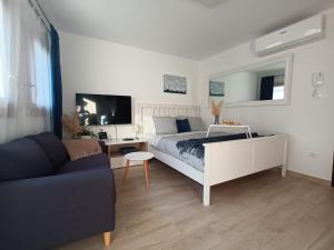 a white bedroom with a bed and a couch at App Hedonist in Novigrad Istria