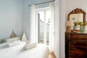 a white bedroom with a bed and a mirror at Castel Abaso Boutique Apartments by Explore Andros in Andros
