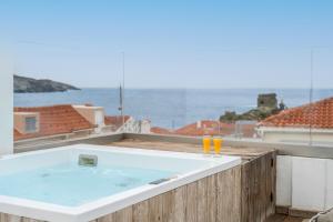 a hot tub on a balcony with a view of the ocean at Castel Abaso Boutique Apartments by Explore Andros in Andros