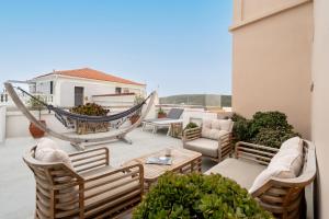a patio with chairs and a hammock on a balcony at Castel Abaso Boutique Apartments by Explore Andros in Andros