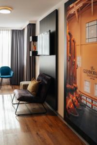 a living room with a chair and a wall with a poster at Hotel de Naaldhof in Oss