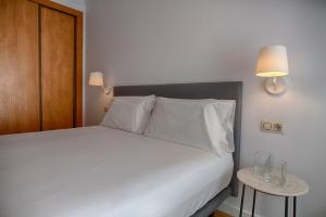 1 dormitorio con 1 cama blanca con 2 lámparas y mesa auxiliar en Sercotel Tribuna Málaga, en Málaga 27 fotos más