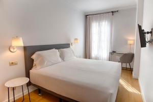 Un dormitorio con una cama blanca grande y una ventana en Sercotel Tribuna Málaga, en Málaga