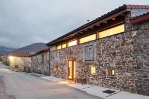 kamienny budynek z ławką obok ulicy w obiekcie Hotel Rural Las Encinas w mieście Santa María de Redondo