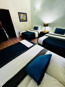 a hotel room with three beds with blue pillows at Casa Lomas en Zona Dorada, 5 minutos de la playa in Mazatlán