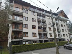 ein Mehrfamilienhaus mit Balkonen an einer Straße in der Unterkunft Apartament Gwiazda przy Stoku na parterze z ogródkiem in Krynica-Zdrój