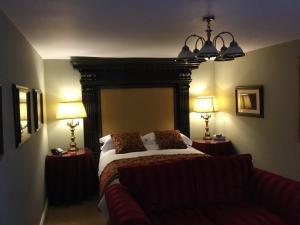 ein Schlafzimmer mit einem Bett, zwei Lampen und einem Sofa in der Unterkunft The Brownlow Arms Inn in Grantham