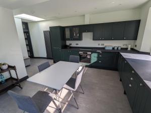 a kitchen with green cabinets and a white table and chairs at Sandstones in North Berwick