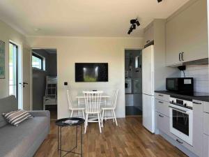 a kitchen and a living room with a table and chairs at Stuga Varberg Södranäs in Varberg