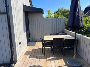 a patio with a table and chairs and an umbrella at Stuga Varberg Södranäs in Varberg +2 photos