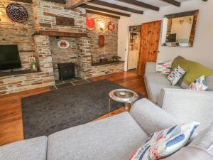 Una sala de estar con dos sofás y una chimenea. en Mews Cottage, en Tintagel