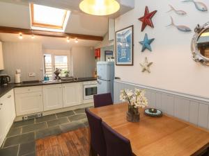 una cocina con una mesa y un refrigerador en Mews Cottage, en Tintagel