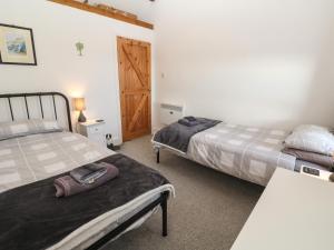Un dormitorio con dos camas y una puerta de madera. en Mews Cottage, en Tintagel