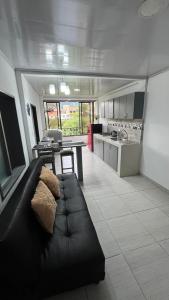 a living room with a black couch and a kitchen at apartamento mirador el paraiso in Santa Rosa de Cabal