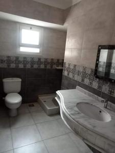 a bathroom with a toilet and a sink and a window at Luxury Villa in North Coast Mediterranean in Dawwār Abū Maḩrūs