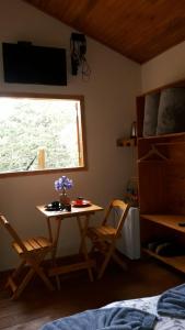 a bedroom with a table and chairs and a window at Cabana refúgio do tico tico 07 in Cunha