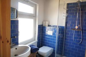 Un baño con azulejos azules, inodoro y lavabo. en Romantik-Ferienhaus -Vier Sterne- idyllische Lage nähe Berlin, en Marienwerder