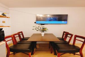a dining room table with chairs and a television on the wall at Hongdae 3mins, Q House in Seoul