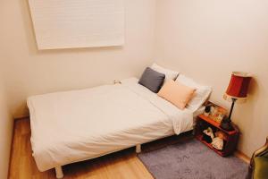 a small bedroom with a bed with white sheets and pillows at Hongdae 3mins, Q House in Seoul +4 photos