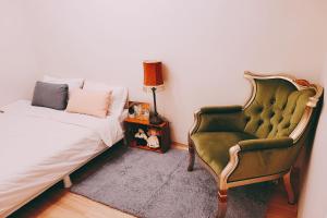 a bedroom with a bed and a green chair at Hongdae 3mins, Q House in Seoul