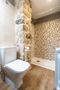 a bathroom with a toilet and a stone wall at Encanto de Valderrobres in Valderrobres +8 photos