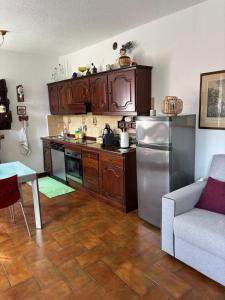 a kitchen with wooden cabinets and a stainless steel refrigerator at Ester Lakehouse, graziosa casa indipendente in Lierna