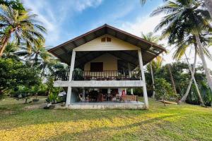 a house with a balcony and palm trees at Baan Nai Bang in Suratthani
