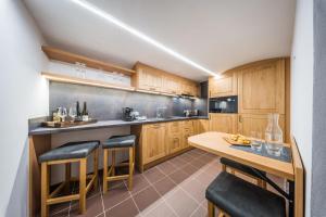 a kitchen with wooden cabinets and a table with bar stools at Vinoza - ubytování a vinný sklep Moravský Žižkov in Moravský Žižkov