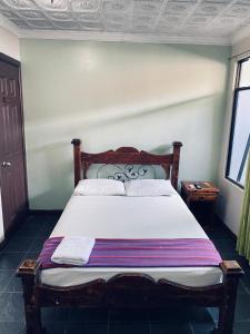 une chambre avec un grand lit avec des draps blancs dans l'établissement Hotel el Tucan Alajuela, à Alajuela