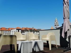 a balcony with white chairs and tables and an umbrella at Casas do Rivoli in Porto