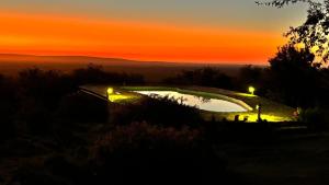 a sunset with a pool on a hill with lights at El Lugar in Travesía